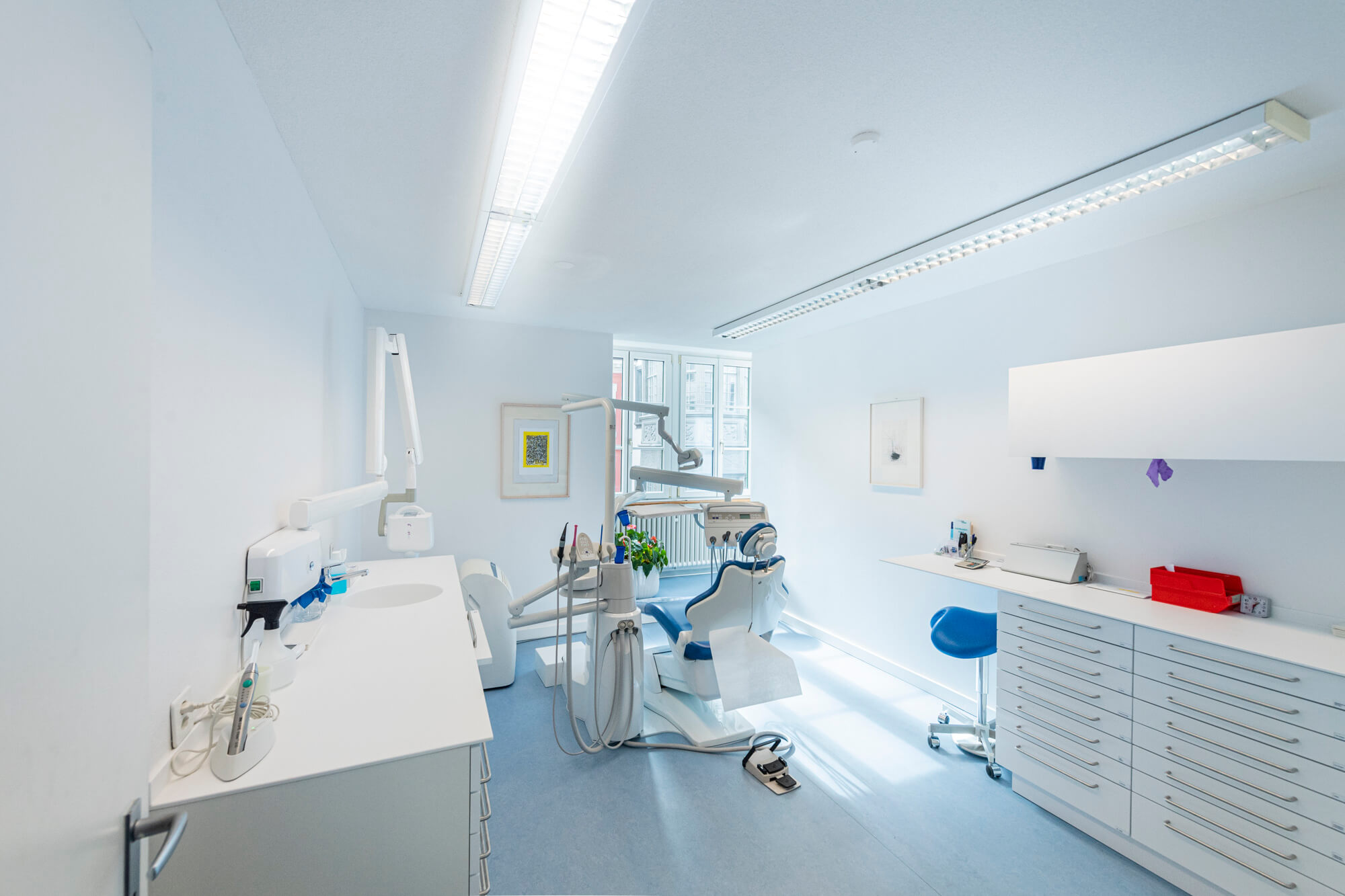 Helles Behandlungszimmer mit blauer Behandlungseinheit und Fenster zur Altstadt